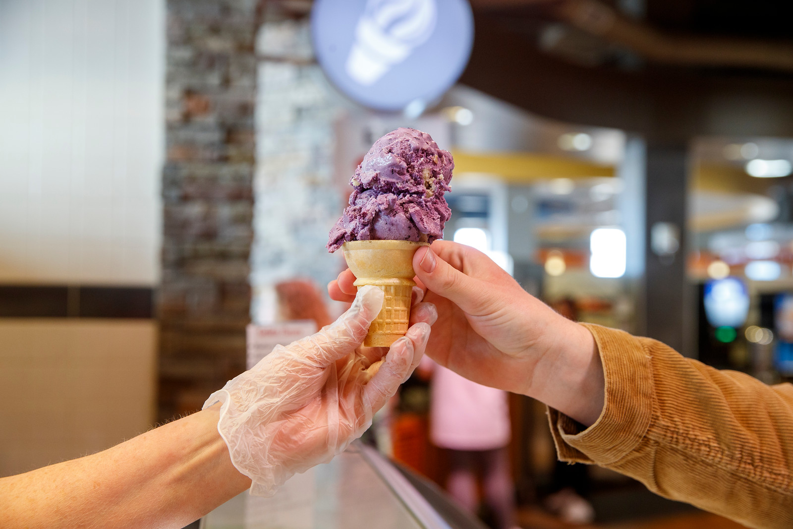 Dining staff member hands a hand dipped gelato cone to a customer