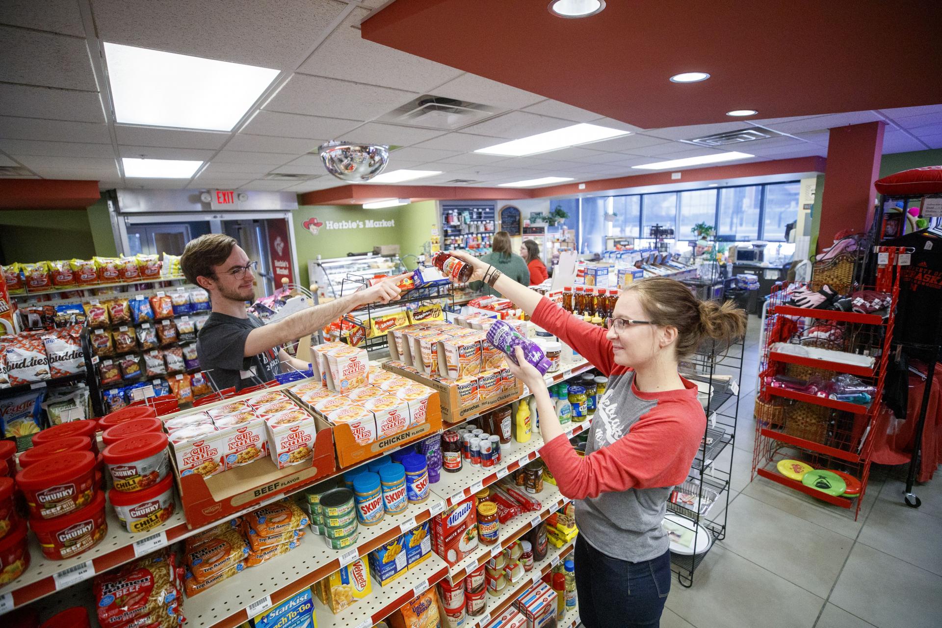 Students pass items across the shelf in Herbie's Market at Village