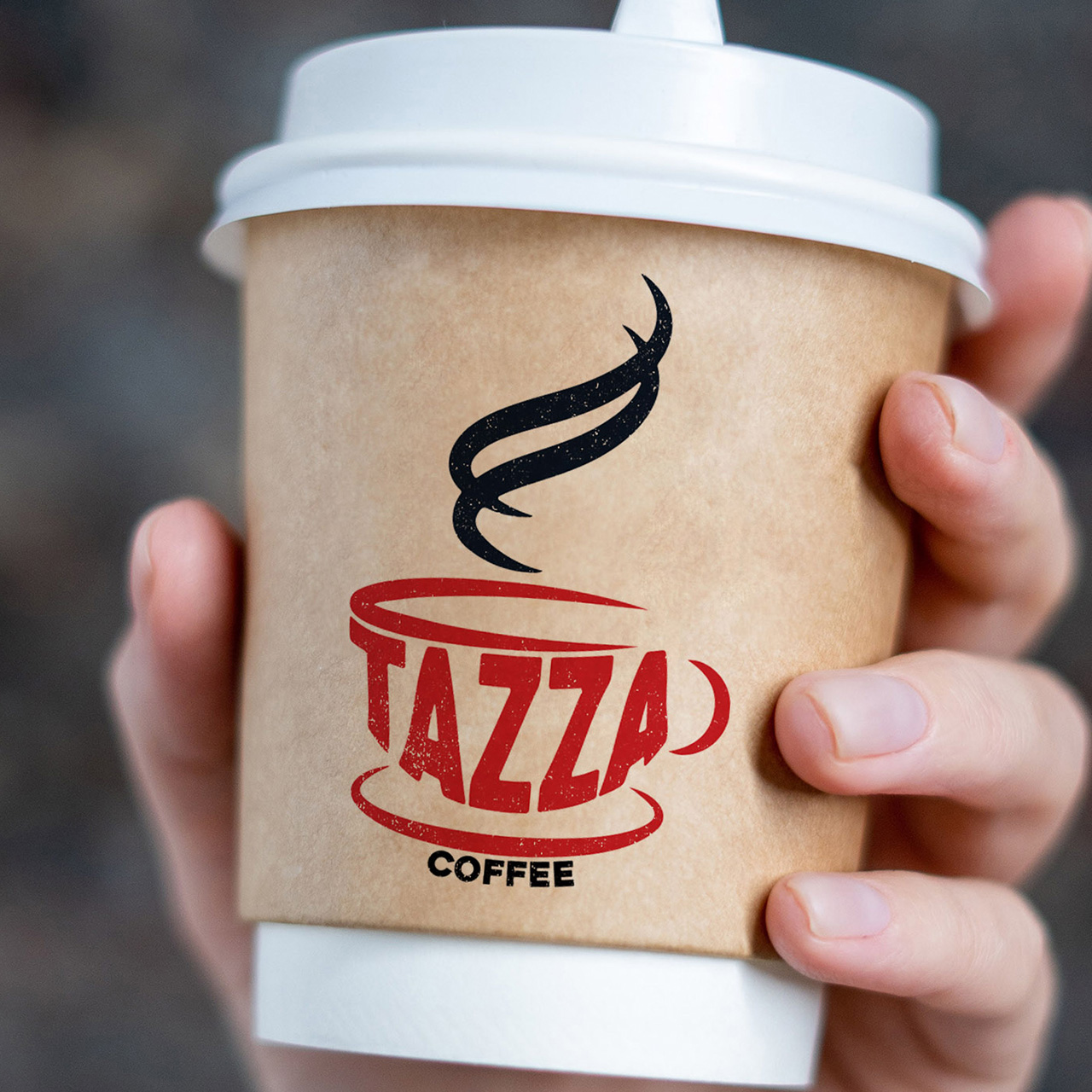A hand holds a Tazza coffee cup