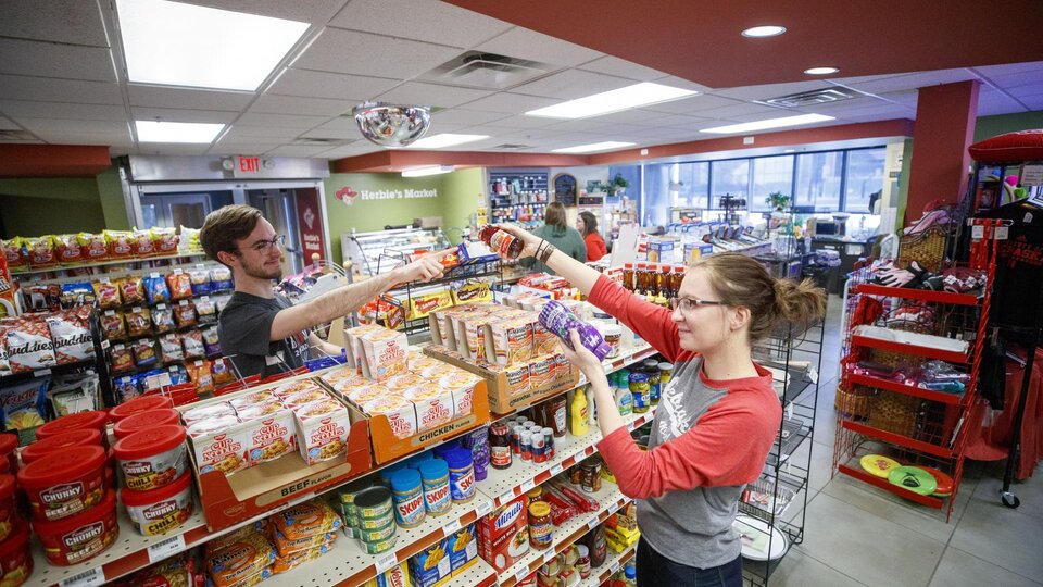 Students pass items across the shelf in Herbie's Market at Village