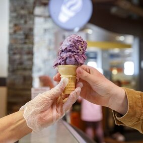 The picture depicts a staff member handing a diner their ice cream cone.