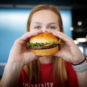 A student is pictured, about to eat a hamburger.