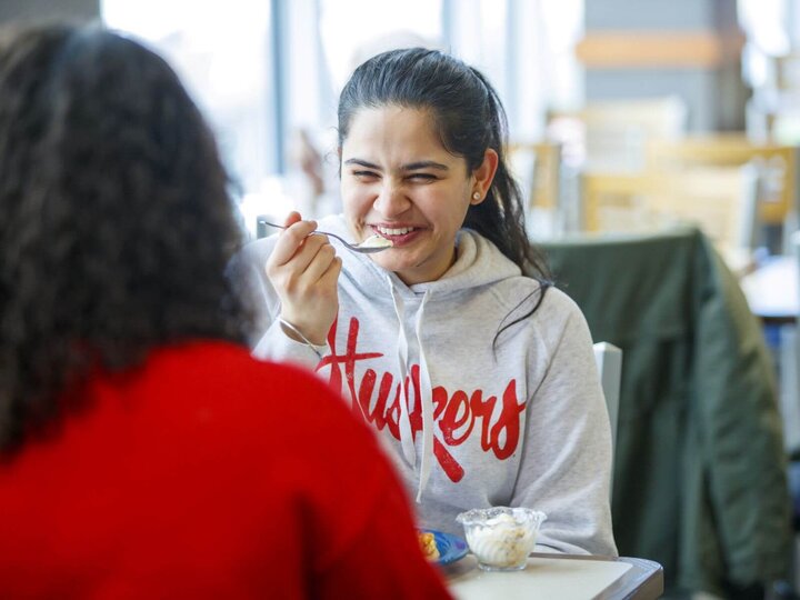 A student smiling while dining on campus.