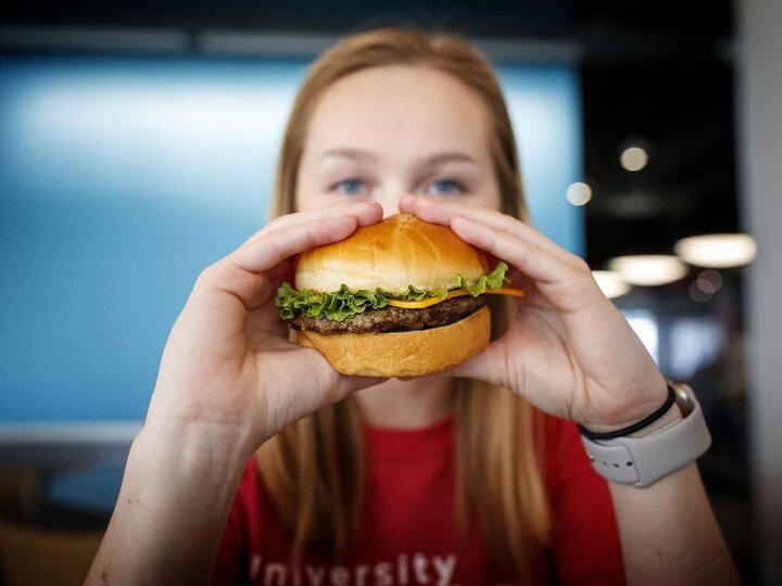 A student is pictured, about to eat a hamburger.