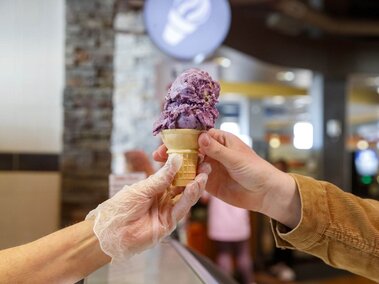 The picture depicts a staff member handing a diner their ice cream cone.